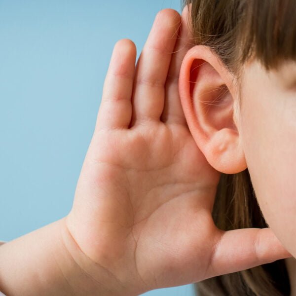 A young girl with her palm over her ear creating awareness of hearing loss in children