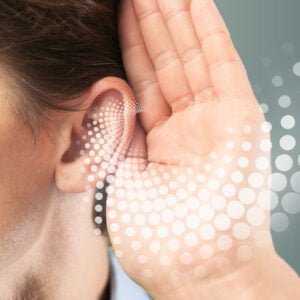 Woman holding her hands near left year showing high frequency hearing loss waves