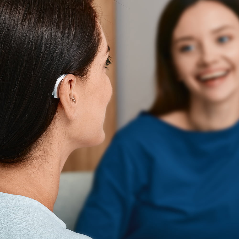 Woman with hearing loss wearing hearing aid having conversation with friend