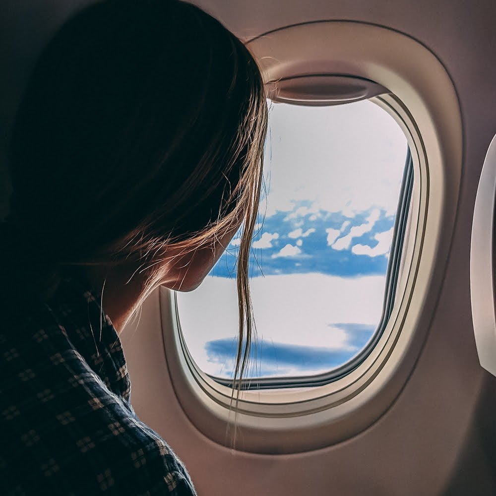 Woman on a plane looking out window (the pressure here could lead to ear barotrauma)