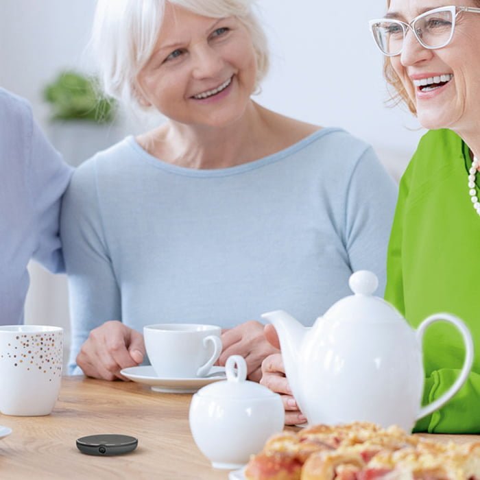 A group of senior friends having fun over a cup of tea while using a Roger microphone