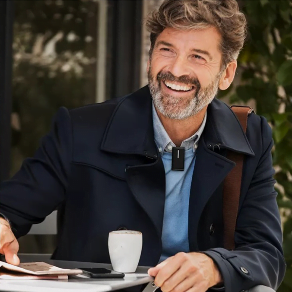 Senior man wearing a clip-on remote microphone at a cafe's listening environments