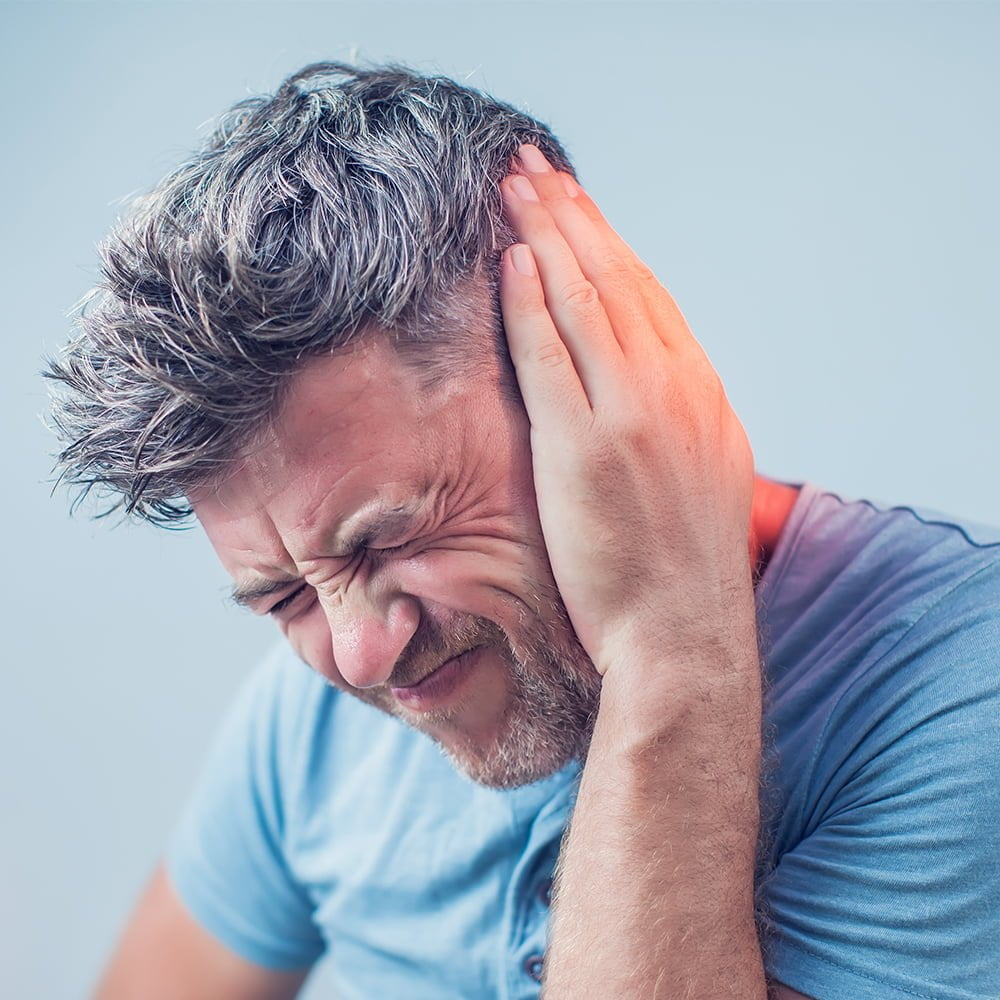 male having ear pain touching his painful head isolated on gray as if tinnitus