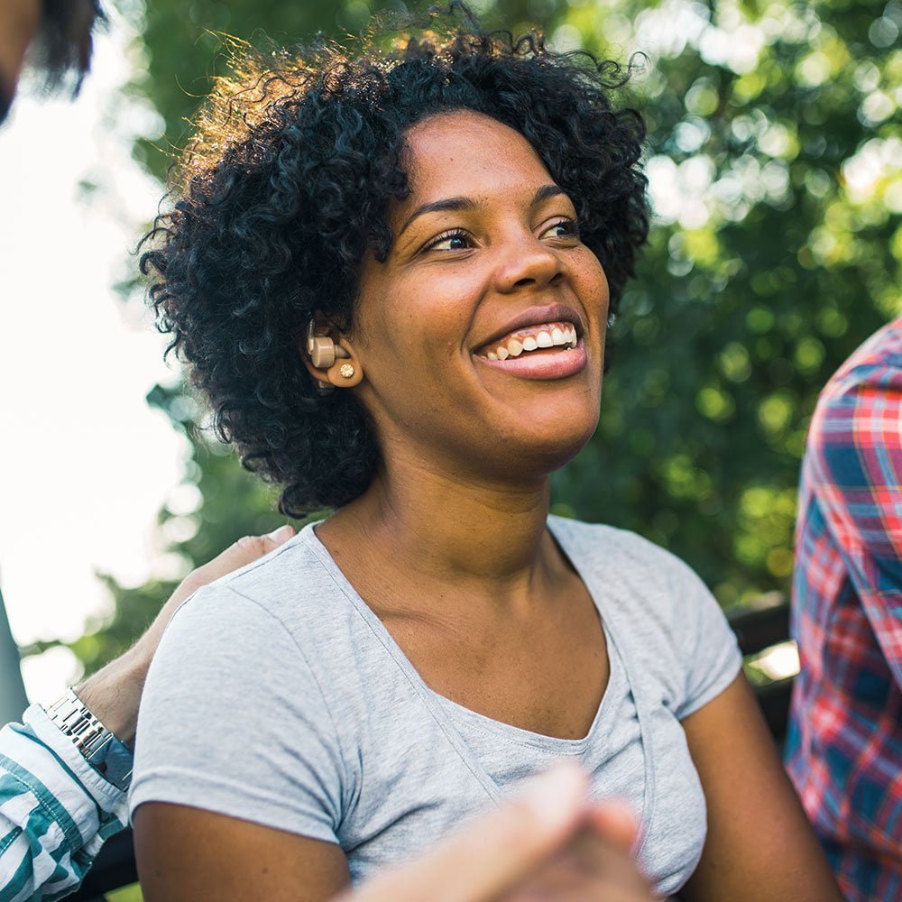 Woman with hearing aid with friends in park