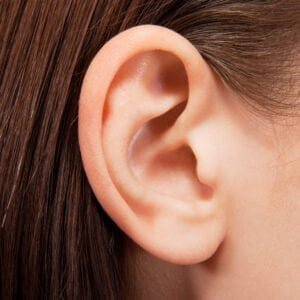 Closeup of ear with brown strands of hair tucked behind it.