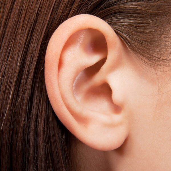 Closeup of ear with brown strands of hair tucked behind it.
