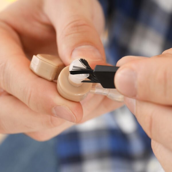 Extreme closeup of hands cleaning hearing aids with a specialised brush